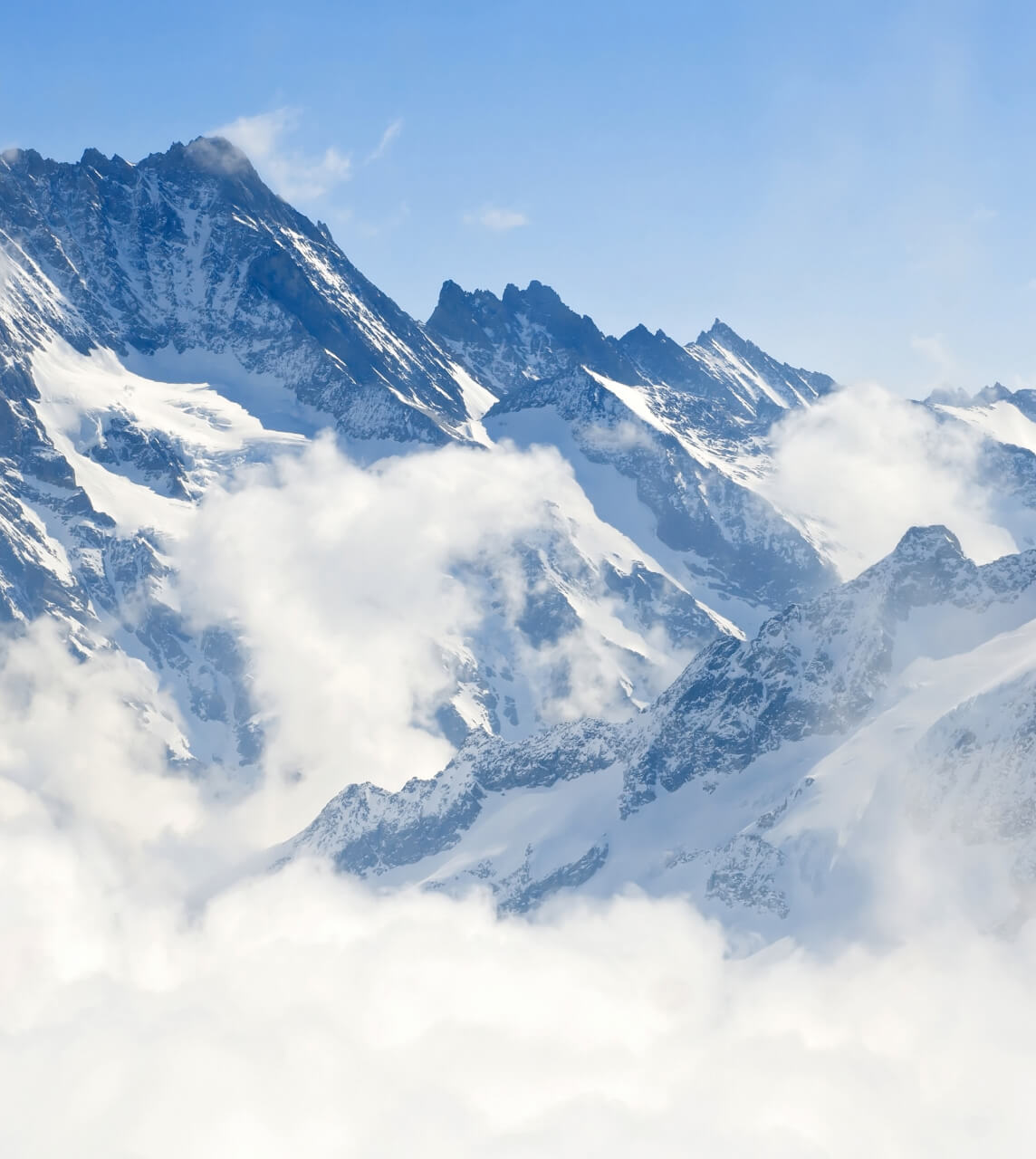 Snowy mountain peaks with clouds and blue sky