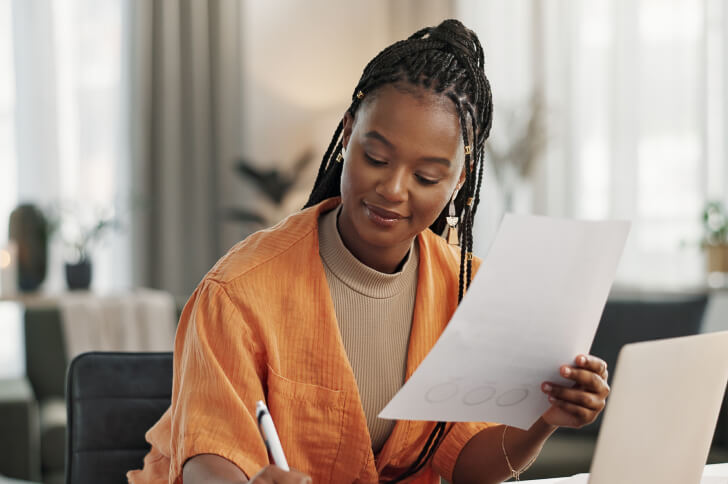 Lady holding a piece of paper and a pen making notes