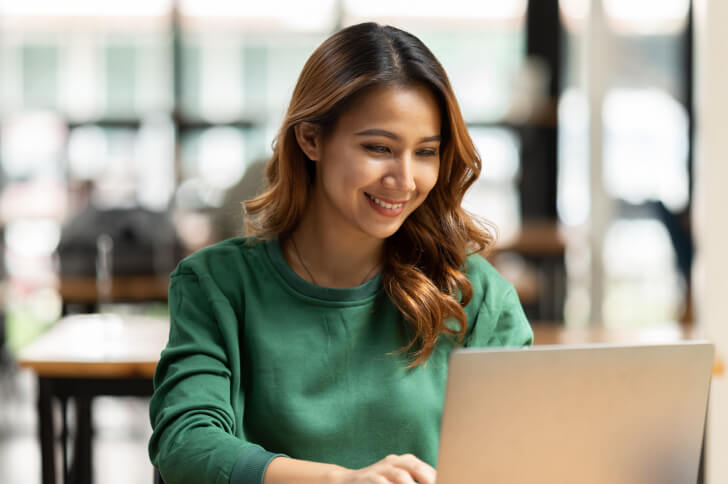 Lady Sat In Front Of A Laptop Working And Smiling