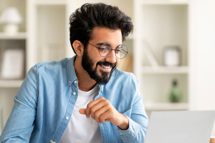 Man In Glasses Smiling Looking At A Laptop Computer